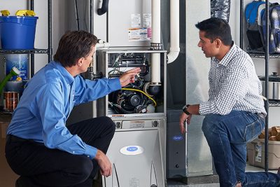 65df8c11f3e4c468cbd351a5_furnace repair vs replacement – Copy HVAC technician explaining furnace repair and maintenance to a homeowner in Bullhead City, AZ